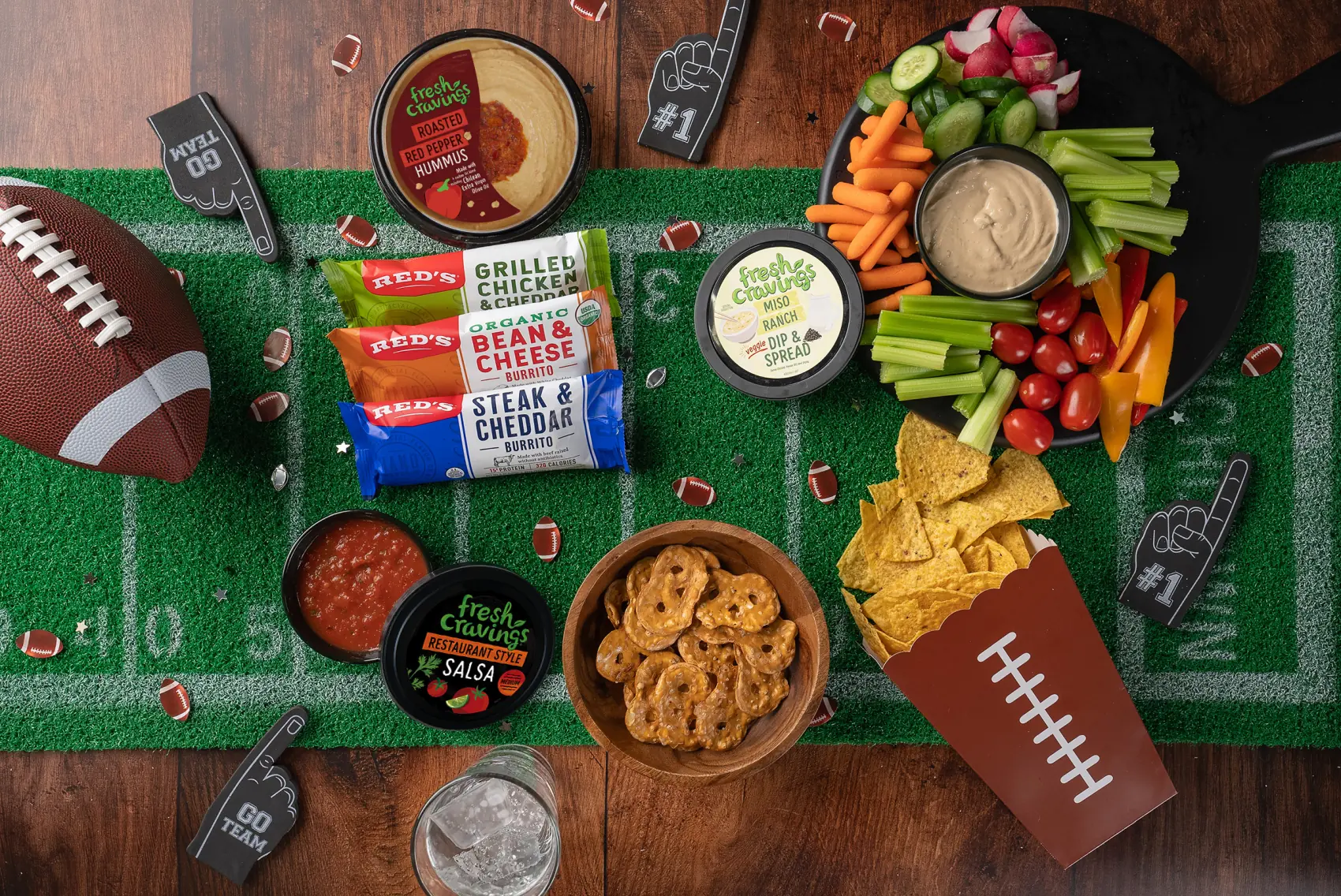 A tailgate spread of snacks and dips laid out on a football-field runner