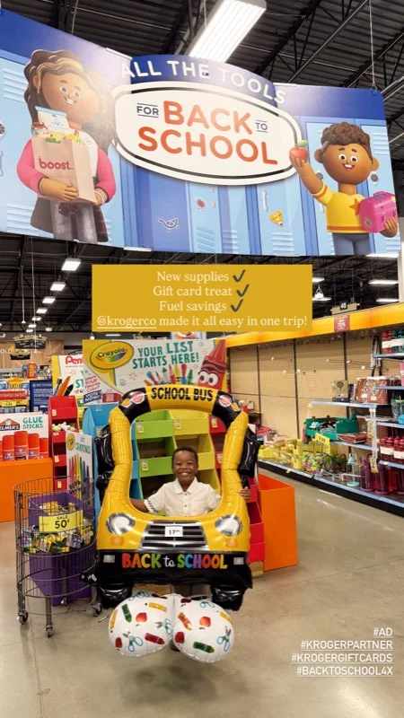 Child posing in a balloon school bus at Kroger for a back-to-school gift card and fuel savings story
