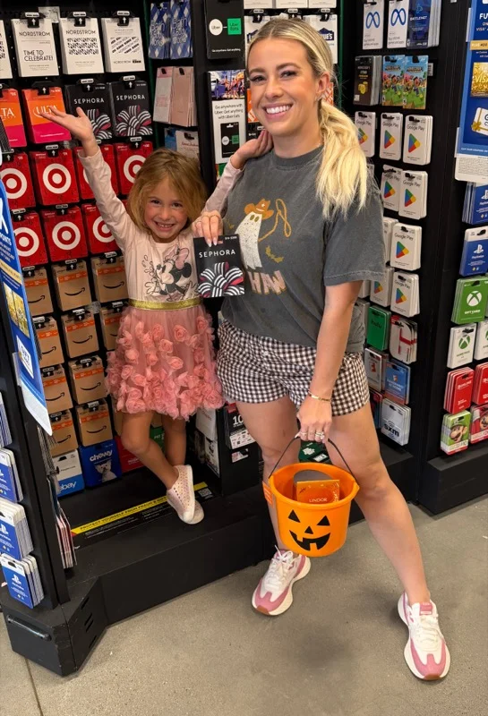 Creator and daughter in the gift card aisle with a Sephora gift card and a Halloween pumpkin bucket